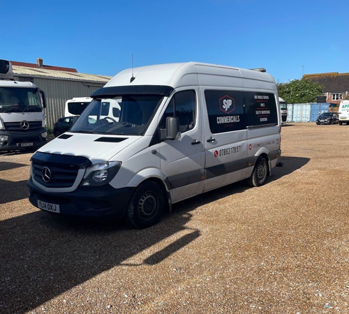 white Mercedes van parked in commercial yard with clear sky